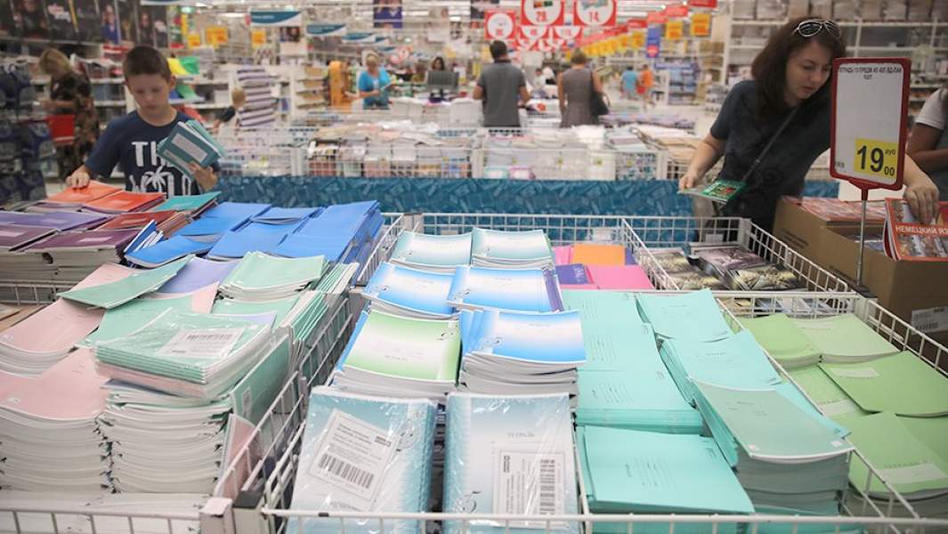 Женщина выбирает школьные тетради в магазине