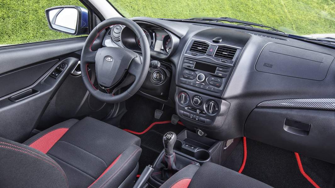 Красные акценты и вставки под углепластик заметно оживляют простенький интерьер