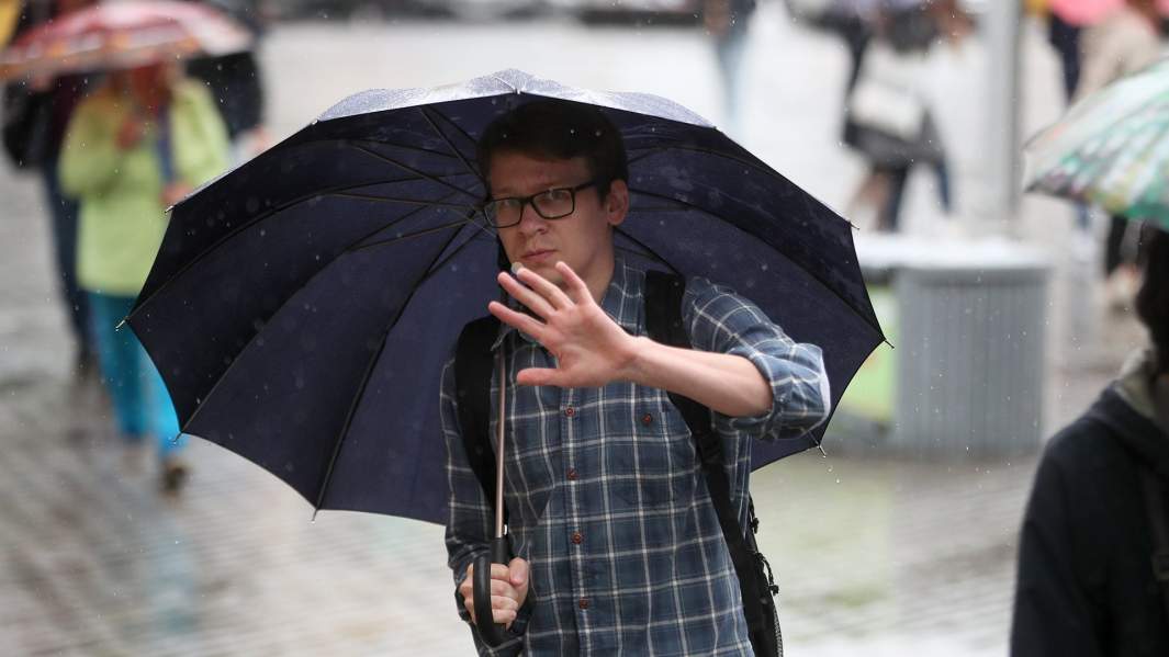 молодой человек пытается закрыть рукой лицо 