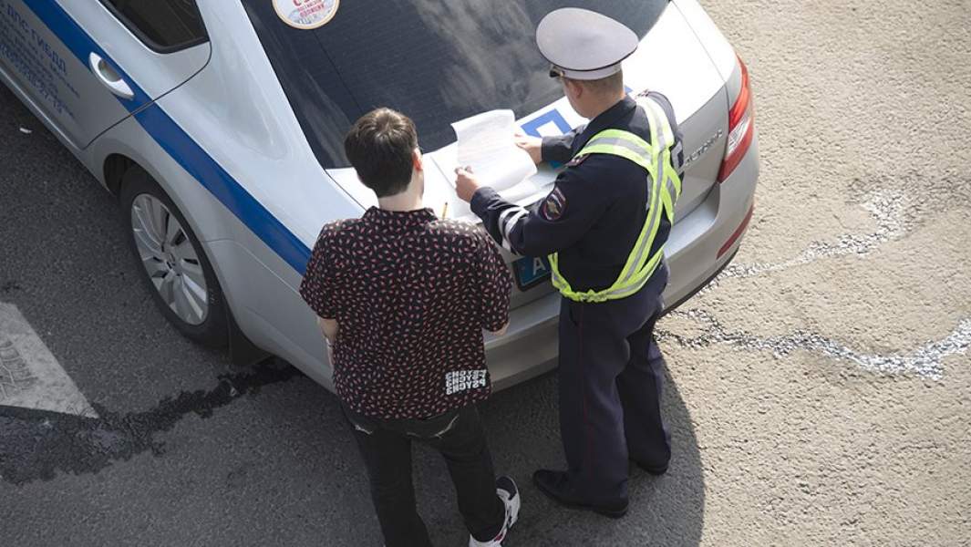 Сотрудник ДПС выписывает штраф нарушителю правил дорожного движения на улице Москвы
