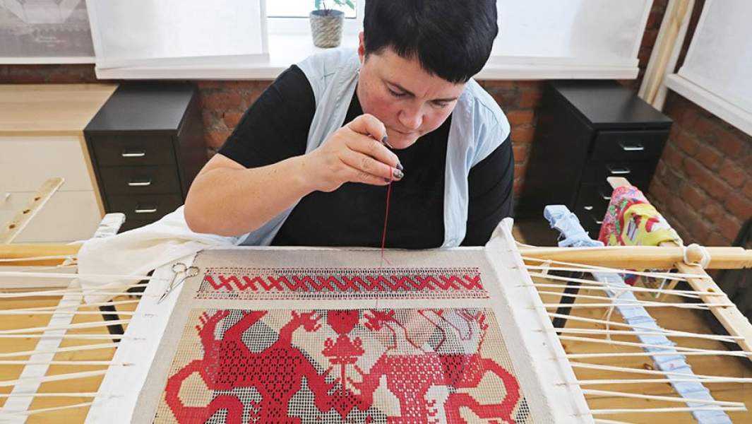 Сотрудница фабрики «Крестецкая строчка» вышивает полотенце