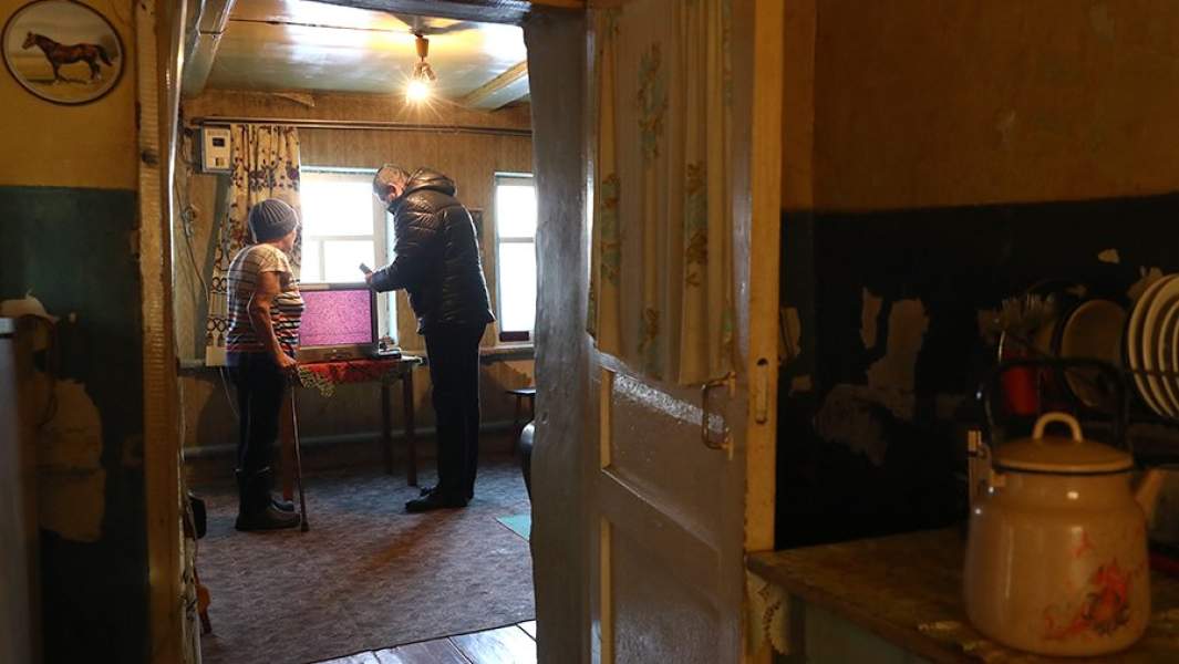 Мужчина помогает пожилой женщине настроить телевизор