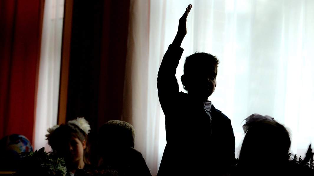 школьник тянет руку во время урока 