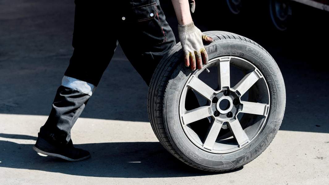 Работник меняет колесо в шиномонтажной мастерской