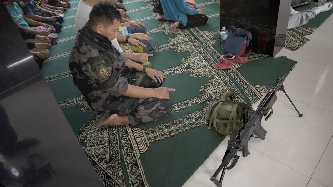 Жители и персонал службы безопасности присутствуют на пятничных молитвах внутри мечети в очищенном районе внутри города, за день до Рамадана, 26 мая 2017 года в городе Марави, на юге Филиппин