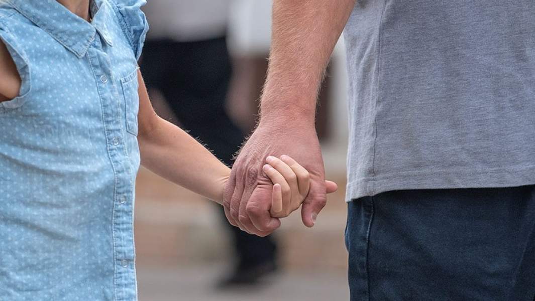 мужик держит за руку девочку