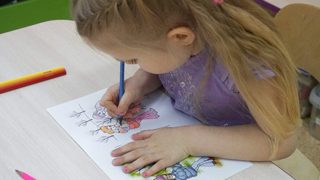 Девочка рисует на занятиях в детском саду 