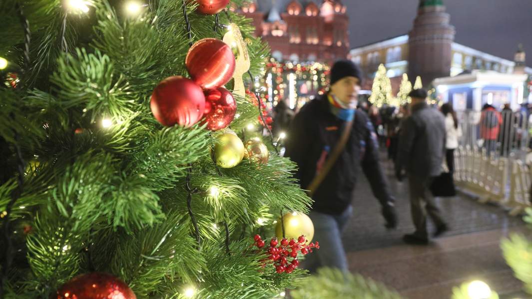 Мужчина идет мимо украшенной елки у Красной площади
