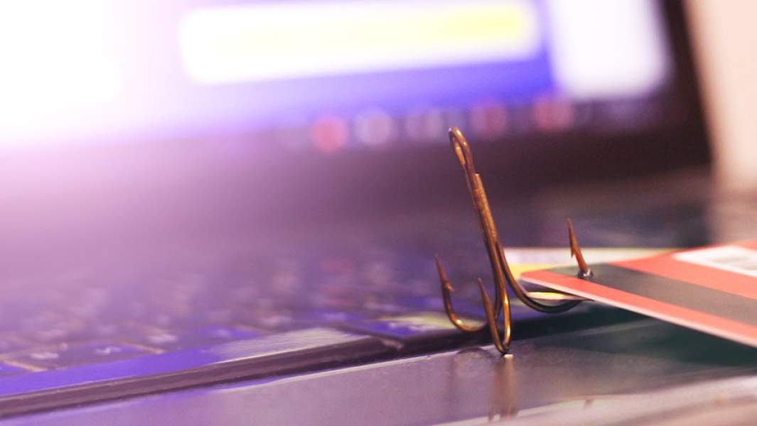 Банковская карта с рыболовным крючком на корпусе ноутбука