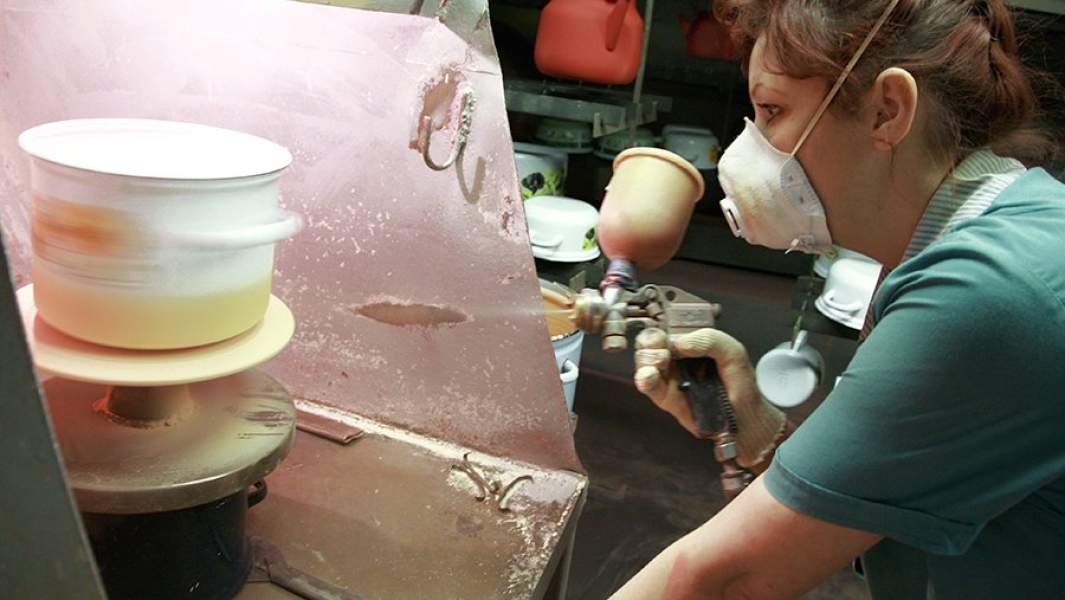 Сотрудница предприятия работает в художественном отделение в цехе эмалированной посуды