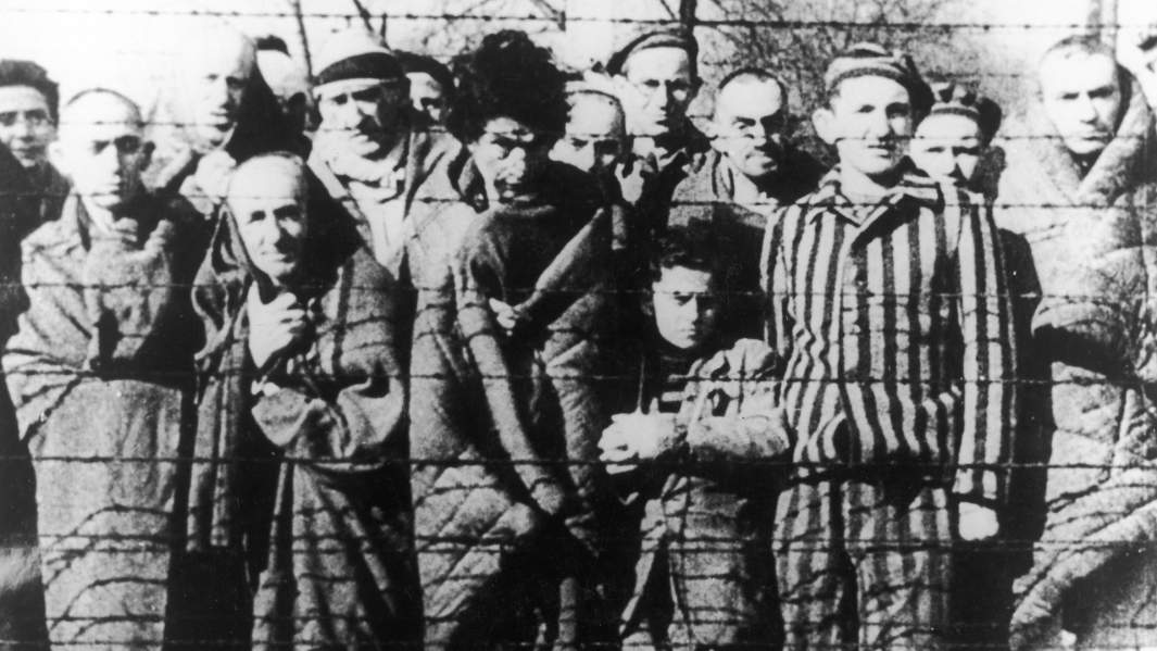 Заключенные концлагеря Аушвиц-Биркенау за колючей проволокой 