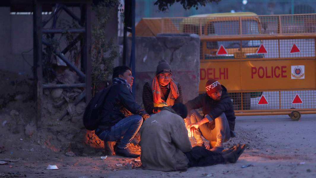Мужчины греются у самодельного костра