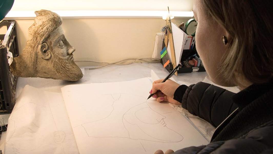 Археолог делает рисунок терракотовой головы мужчины, найденной у мыса Ак-Бурун