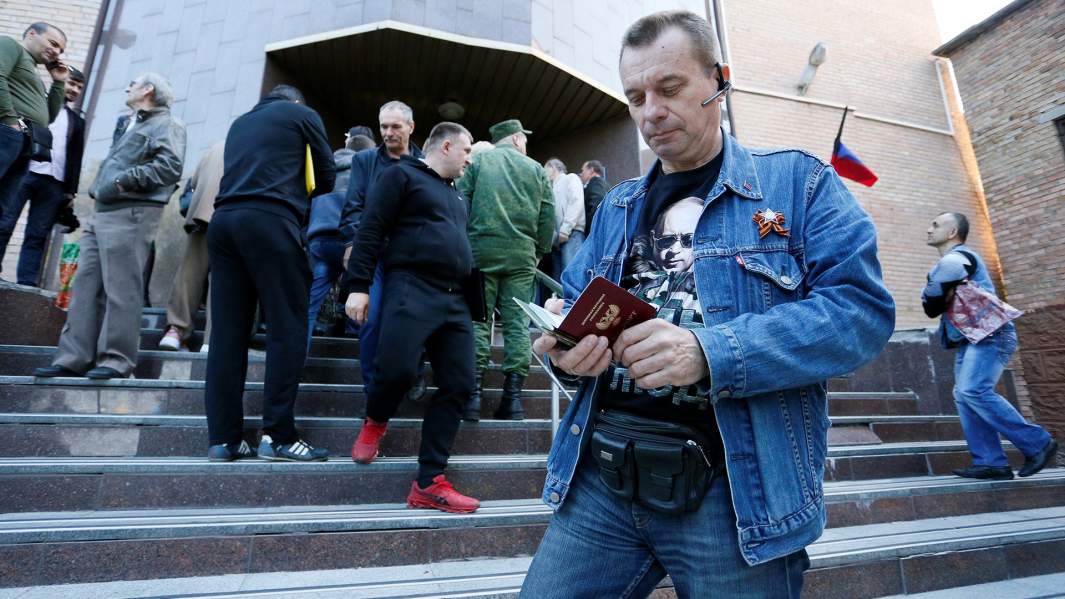 Мужчина держит паспорт у здания миграционной службы в Донецке