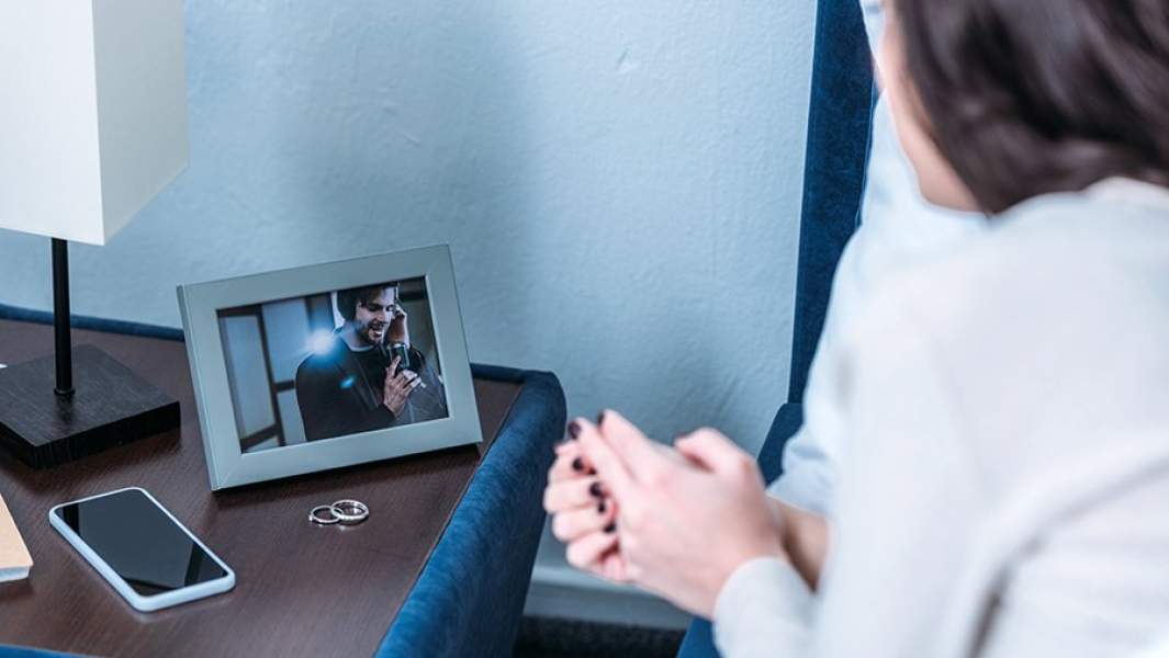 Женщина скорбит, глядя на фотографию умершего мужа