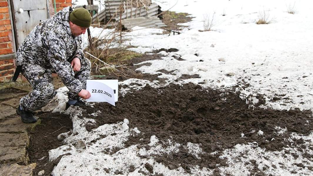 Офицер Совместного центра контроля и координации (СЦКК) ДНР фиксирует воронку от взрыва после артобстрела