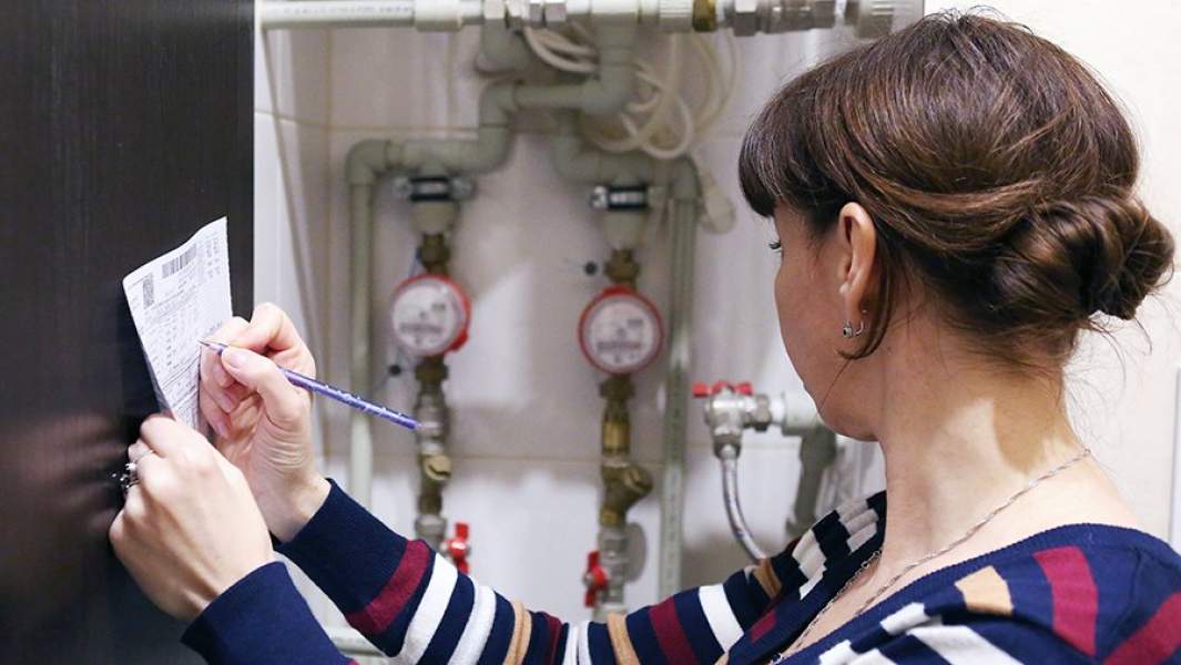 Женщина переписывает показания счетчика учета воды