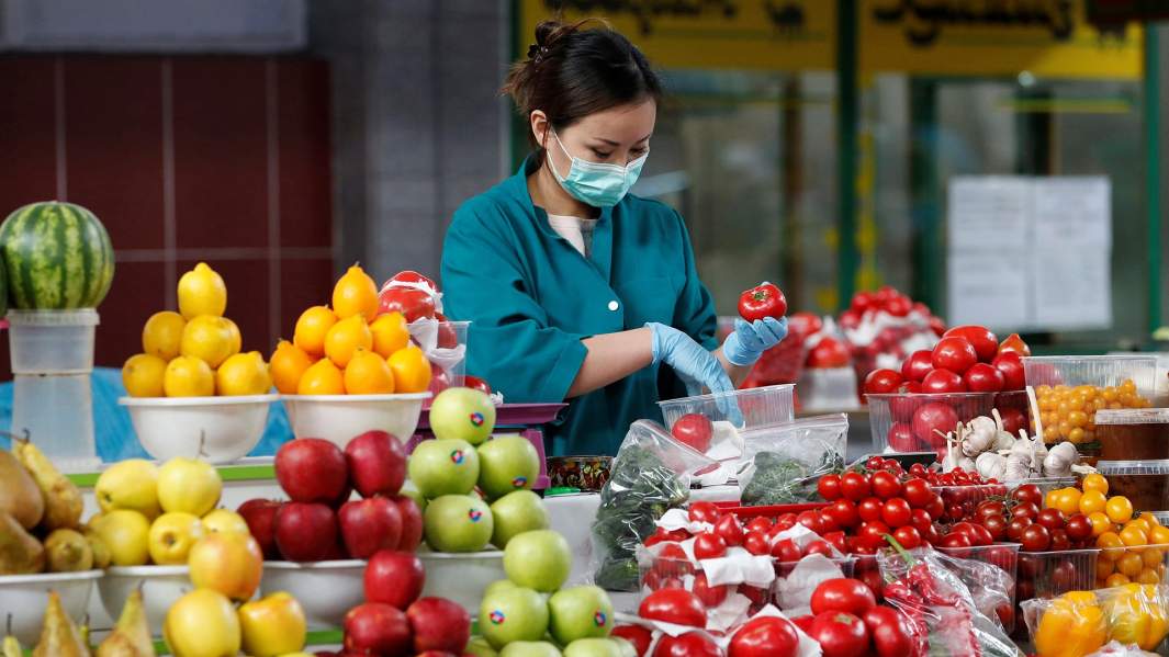 Продавец в защитной маске на продовольственном рынке в Алма-Ате