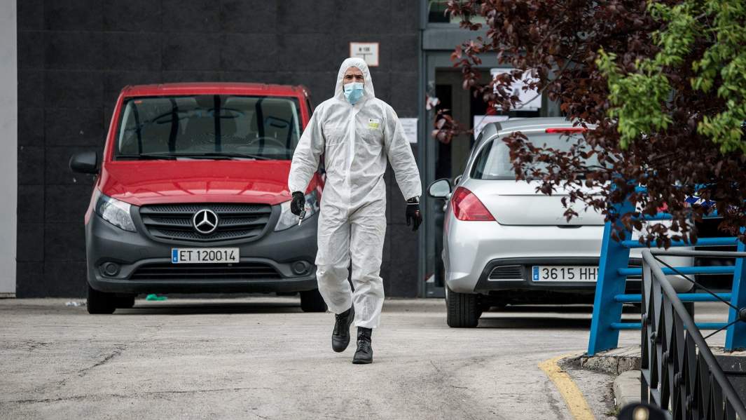 Военнослужащий Испании в защитном костюме около торгового центра Palacio de Hielo, который используется испанской армией в качестве морга