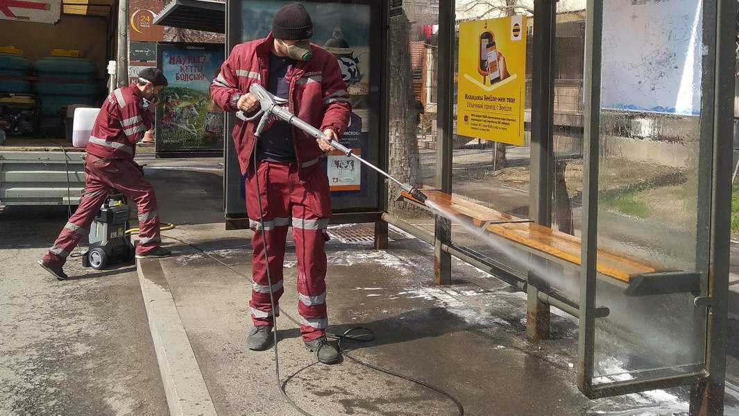 Сотрудники коммунальной службы проводят санитарную обработку остановок общественного транспорта в городе Алма-Ата