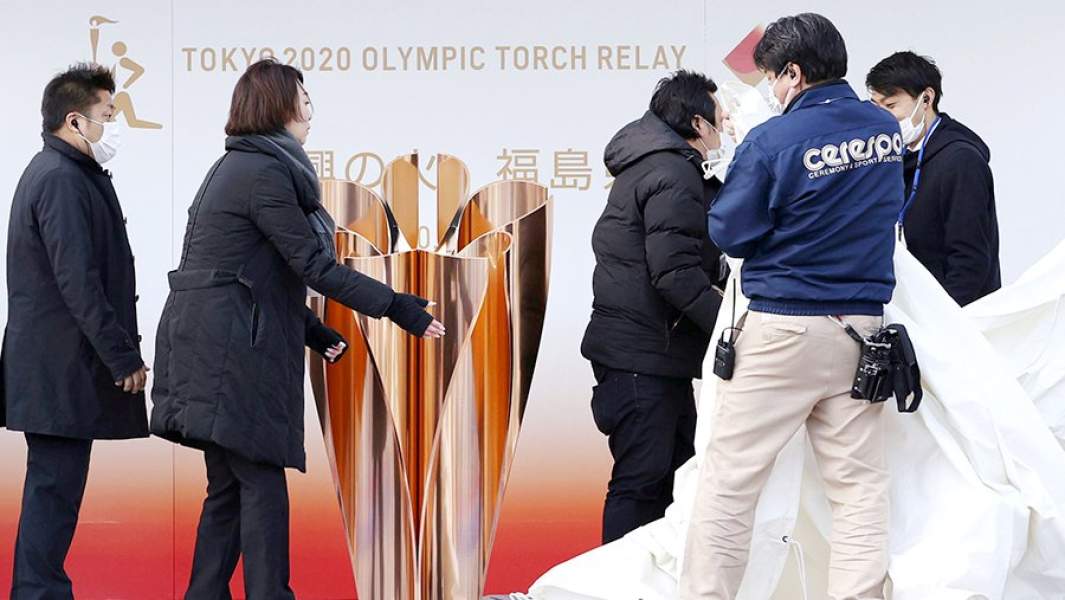 Сотрудники убирают чашу для олимпийского огня после объявления о переносе Летних Олимпийских игр–2020 на 2021 год