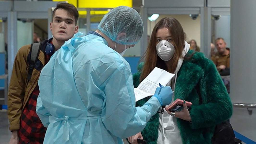 Медицинский работник в костюме полной химической защиты во время осмотра пассажиров в зоне прилета терминала F аэропорта Шереметьево