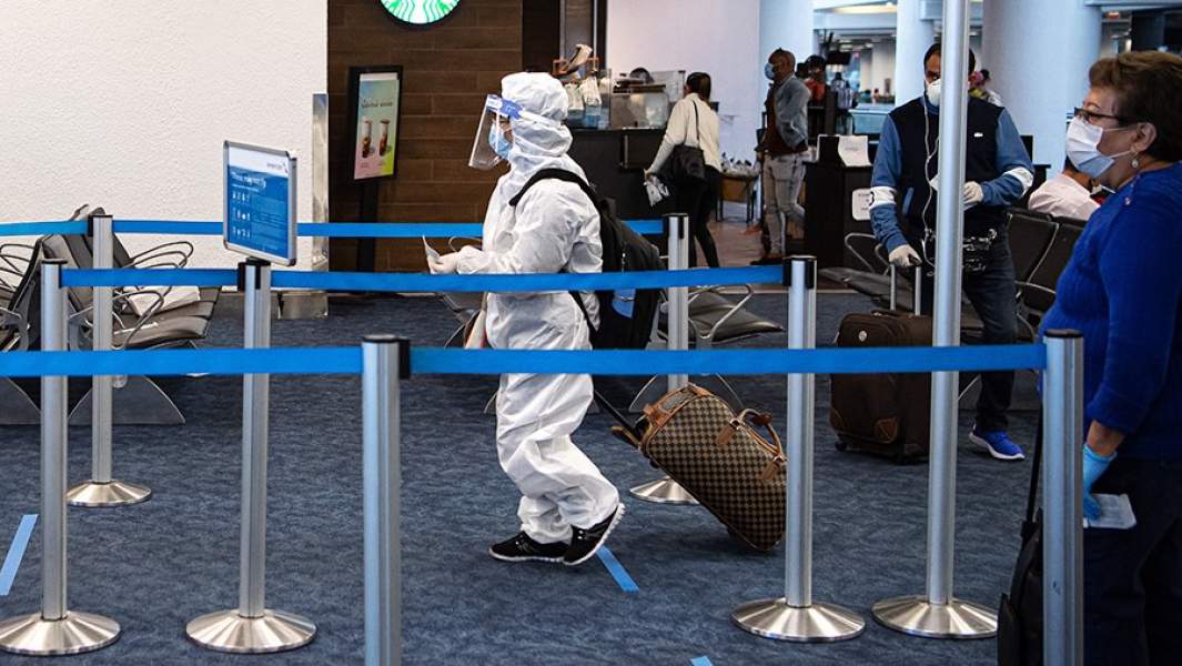 Пассажиры в защитных костюмах в аэропорту