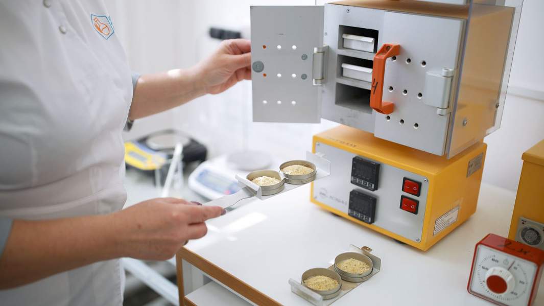 Сотрудница "Центра контроля качества" в Краснодарском крае помещает измельченные образцы сельхозпродукции в сушильную машину для проведения лабораторных исследований их качества и безопасности