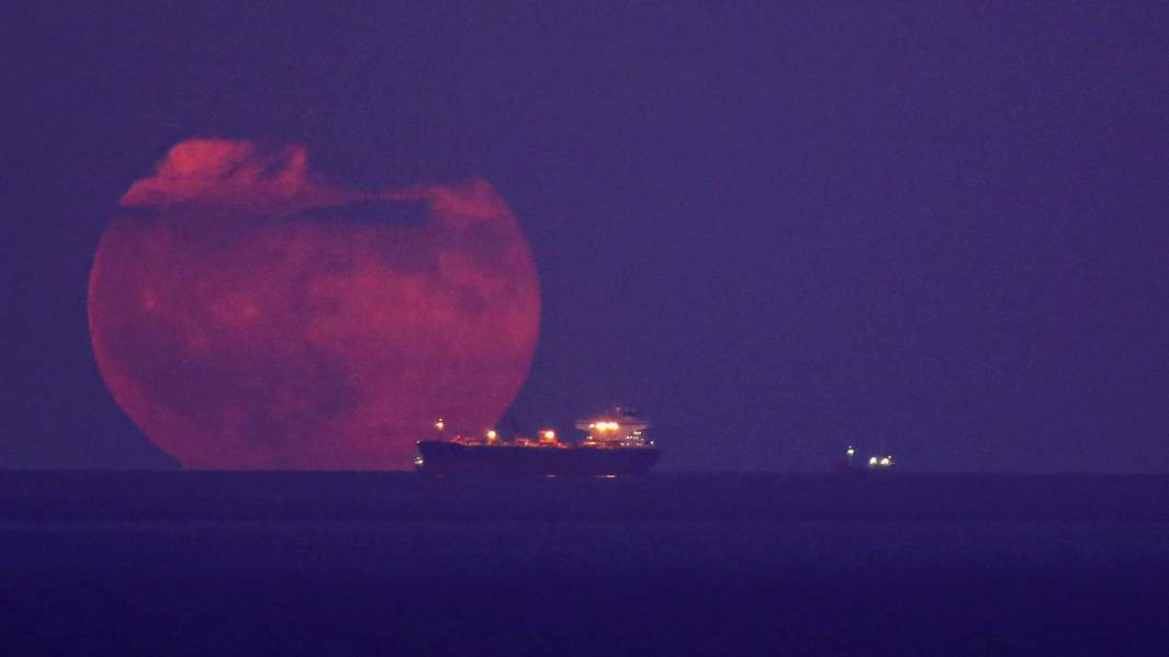 Полная луна восходящая за нефтяным танкером