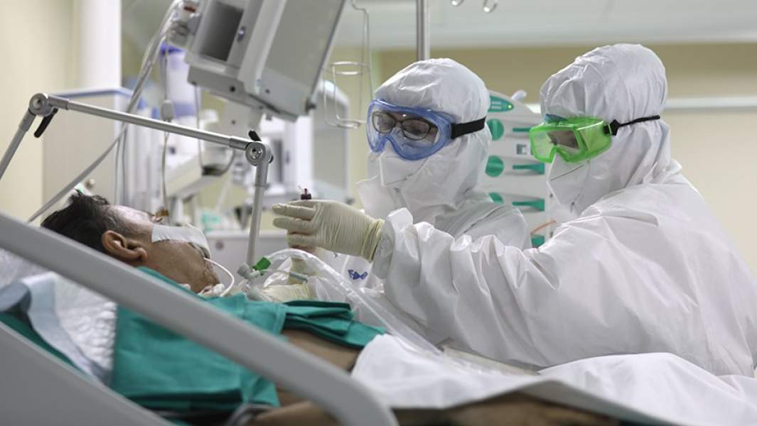 Медицинские работники возле кровати пациента в отделении реанимации и интенсивной терапии