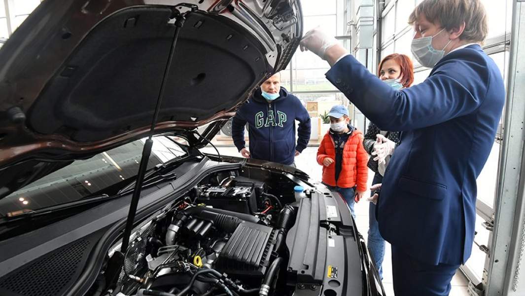 Посетители автосалона осматривают автомобиль