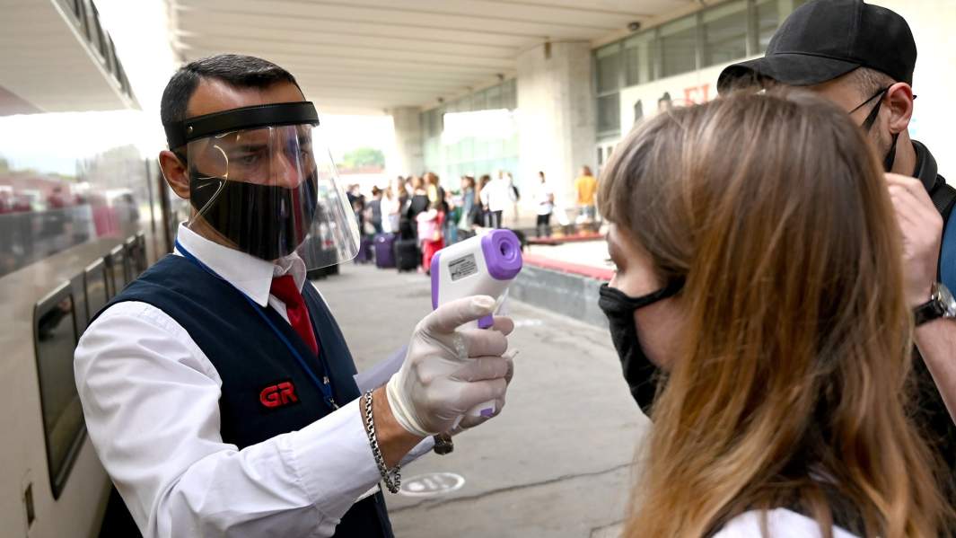 Проводник проверяет температуру у пассажиров на железнодорожном вокзале в Тбилиси