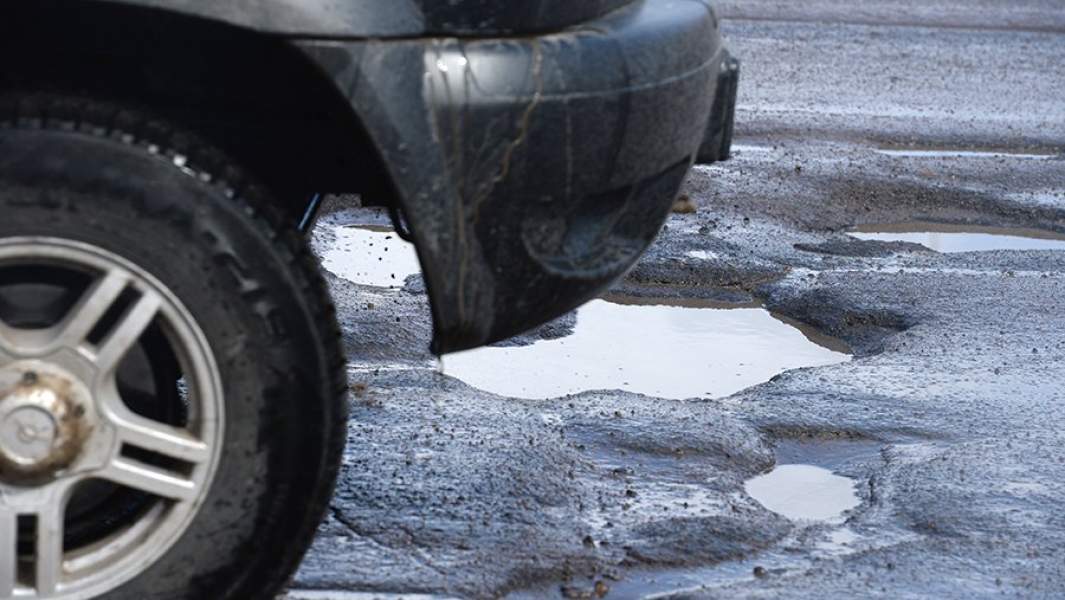Автомобиль едет по разбитому дорожному покрытию