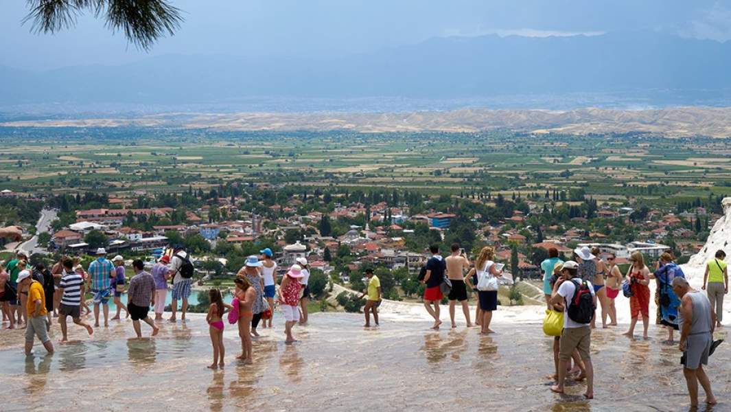 Туристы в травертинах, природных известковых бассейнах, находящихся в природном объекте Памуккале на юго-западе Турции