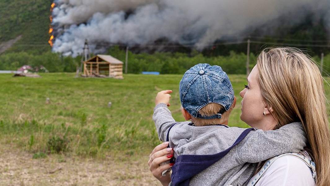 Местные жители наблюдают за лесным пожаром в районе поселка Эссо Быстринского района Камчатского края