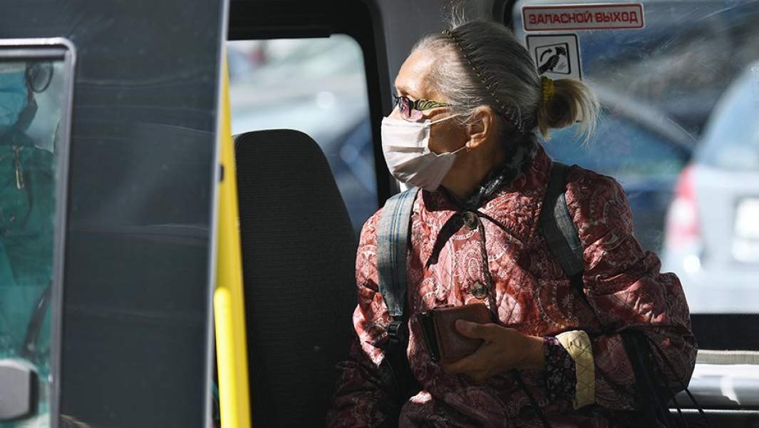 Пожилая женщина в медицинской маске в салоне маршрутного такси