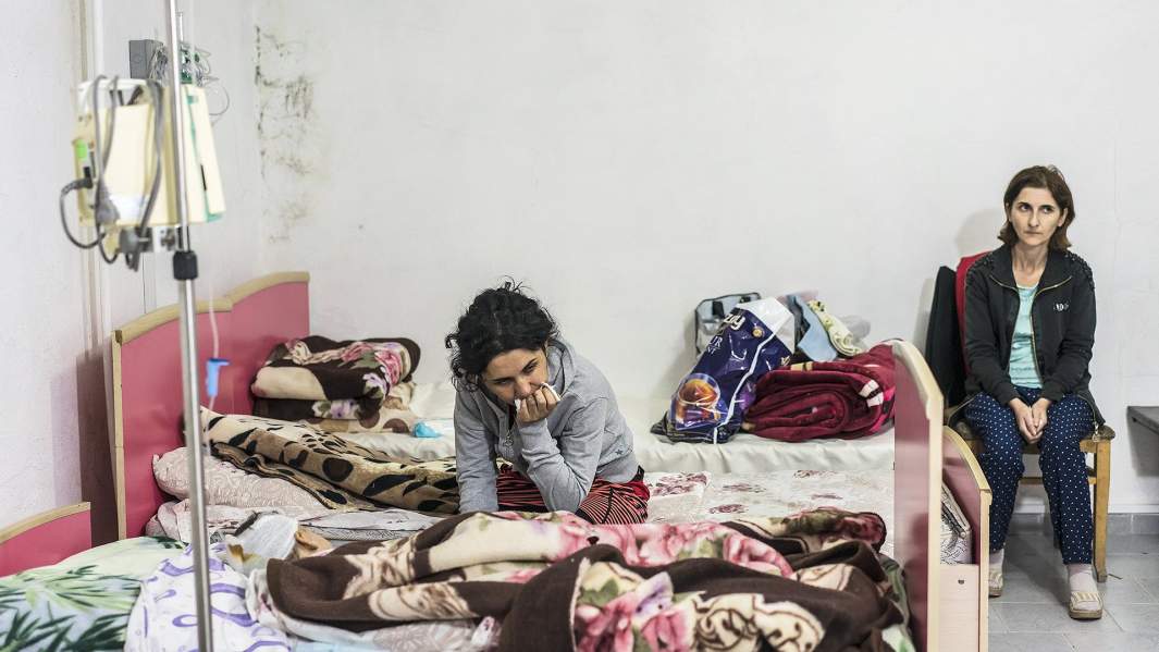 Женщина сидит рядом с раненным сыном в одной из больниц Степанакерта