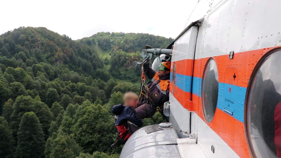 Спасатель ЮРПСО МЧС РФ эвакуирует потерявшегося ребенка с помощью вертолета с горы Ачишхо возле Сочи