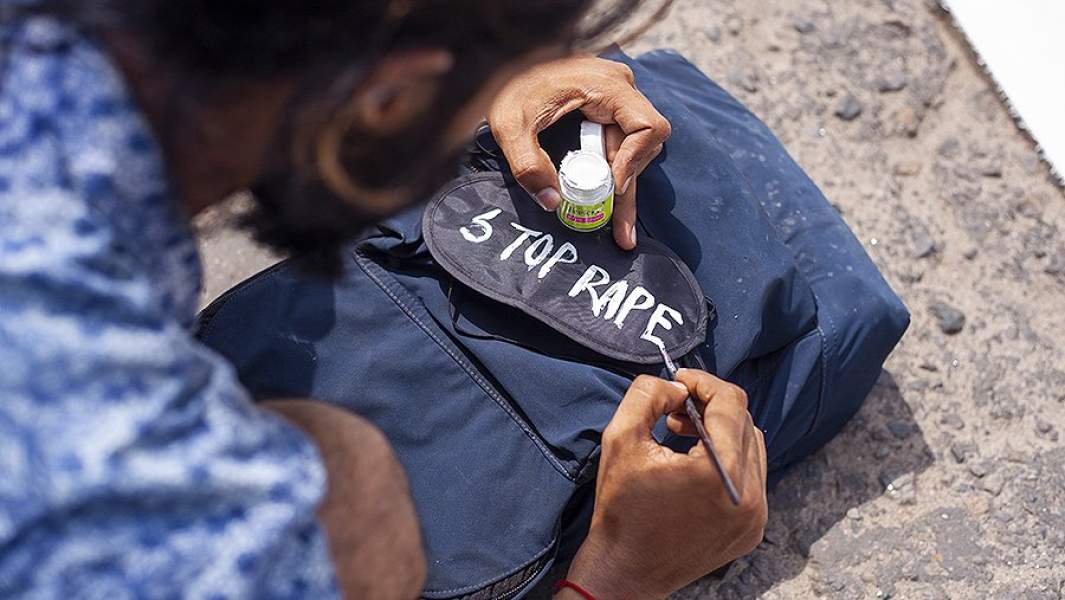 Протестующий в Дакке пишет на маске «Прекратите изнасилования»