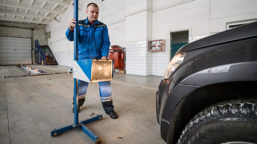 Сотрудник станции ТО проводит технический осмотр автомобиля