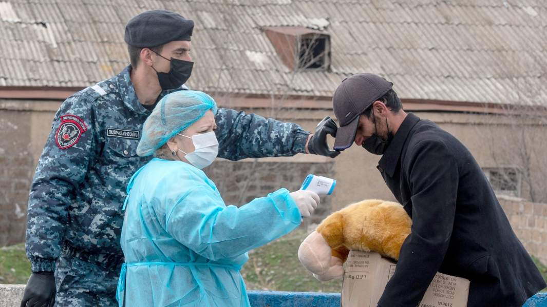 Медицинский работник проверяет температуру у прохожего на КПП на выезде из армянского Эчмиадзина (Вагаршапат)