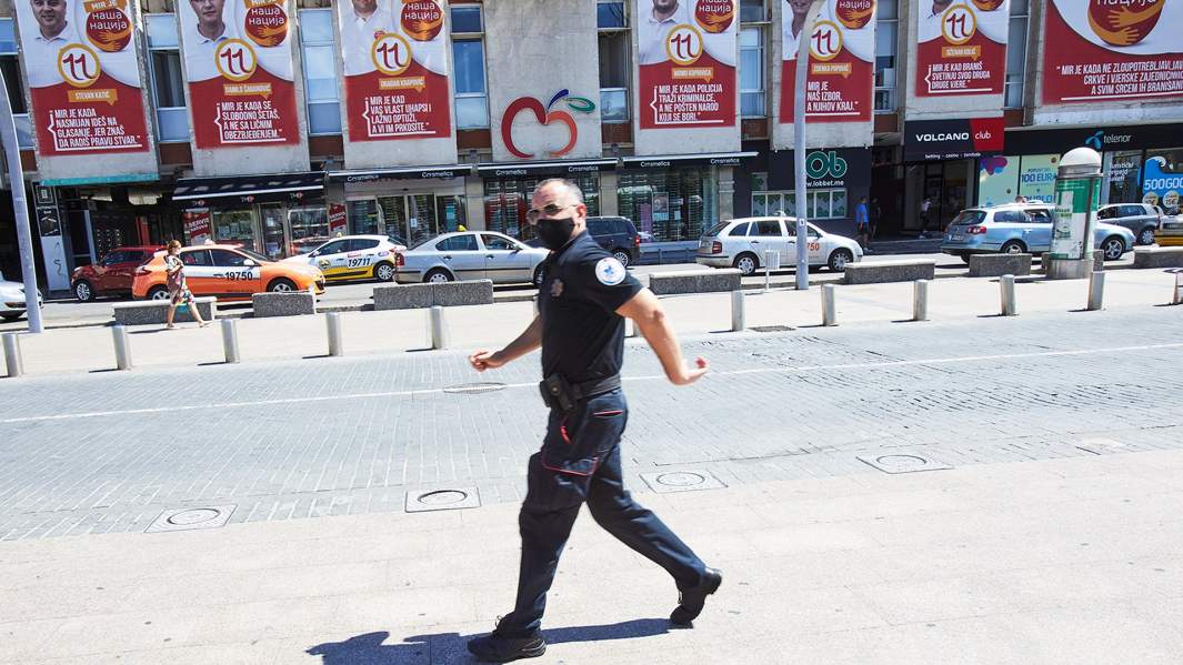 Полицейский проходит мимо агитационных плакатов сторонников оппозиционной партии в Подгорице