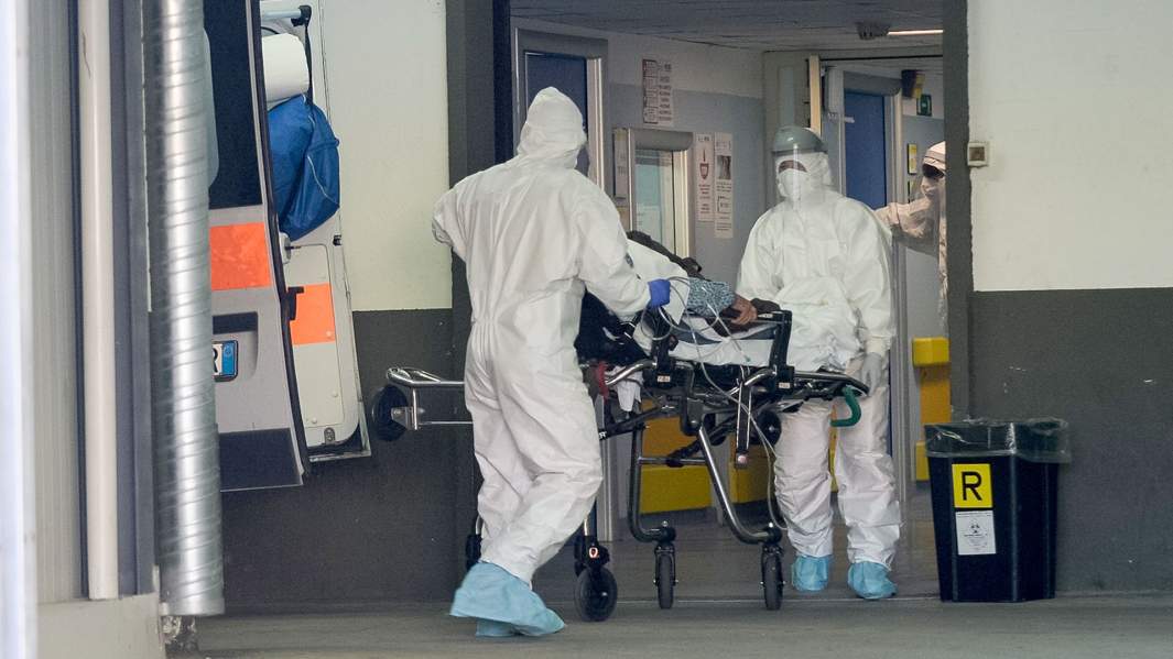 медсестры в комбинезоне, перчатках и антивирусных масках, доставляют пациента с коронавирусом в больницу Covid в Россано, Италия