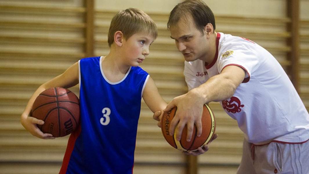Тренер и юный баскетболист на занятиях в специализированной детско-юношеской школе