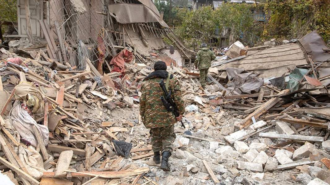 Вооруженные люди возле дома, разрушенного в результате обстрела Степанакерта