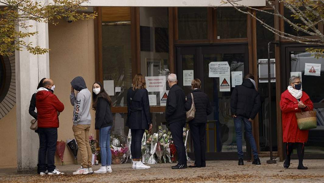 Местные жители возлагают цветы и свечи к зданию школы Bois d'Aulne в память об убитом учителе