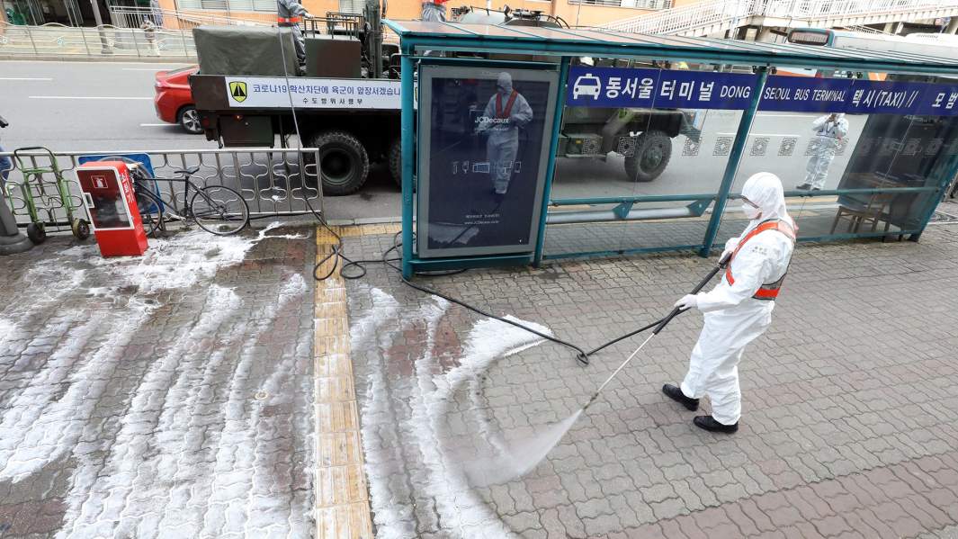 Рабочий проводит дезинфекцию возле автовокзала в Сеуле