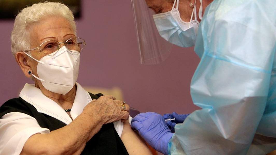 Медицинский работник делает прививку от COVID-19 96-летней жительнице дома престарелых в Гвадалахаре Араселе Росарио Идальго