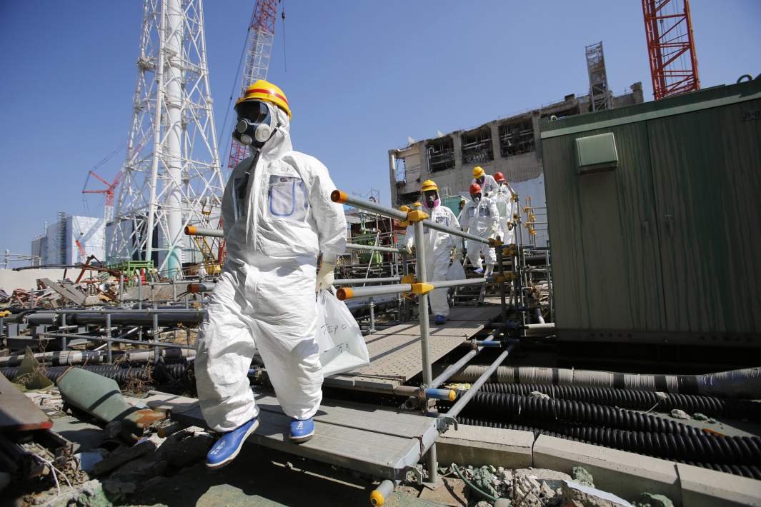 Журналисты в защитных костюмах и масках осматривают электростанцию Фукусима