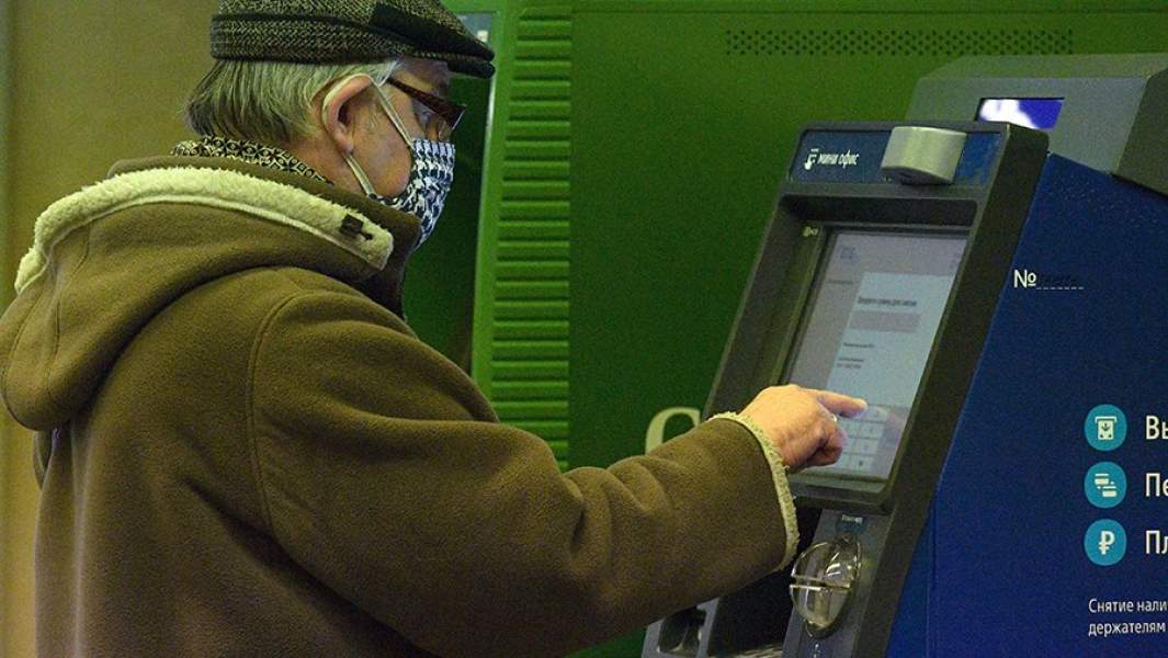 Мужчина в маске у банкомата